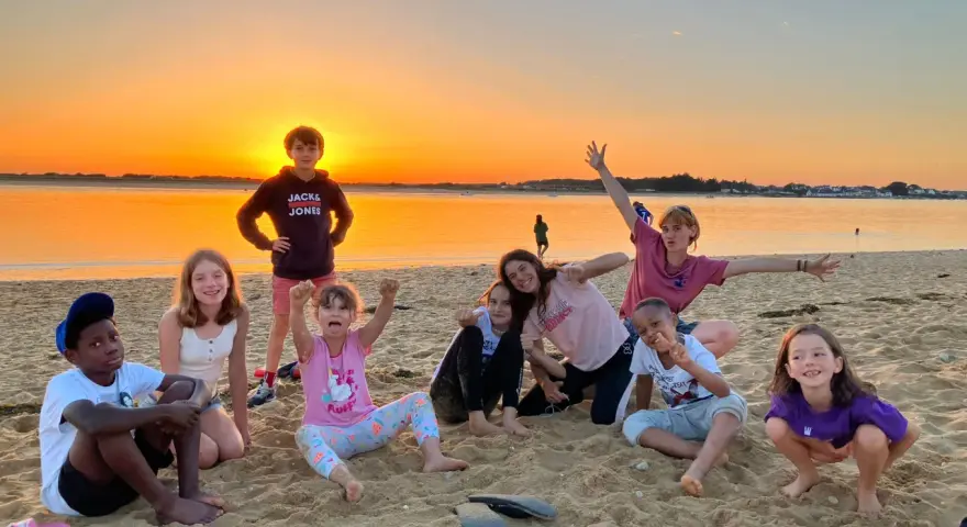 Groupe d'enfants joyeux sur une plage au coucher du soleil.
