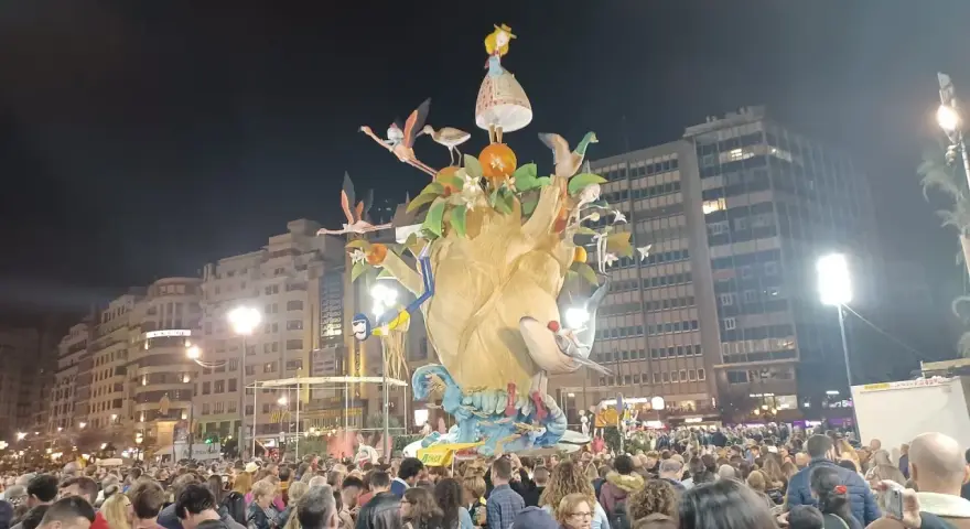 La foule admire une immense sculpture colorée, une scène typique du déroulement des Fallas de Valencia, avec des flamants roses et une petite fille perchée en haut.