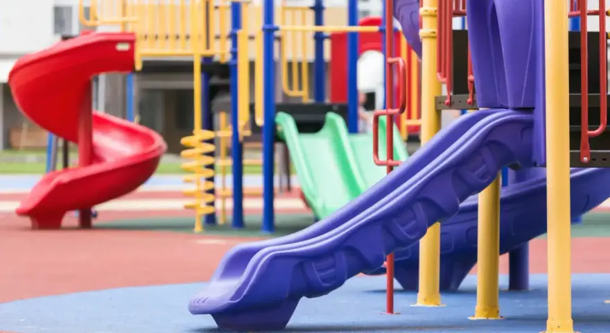 Aire de jeux colorée avec toboggans rouge, vert et violet.