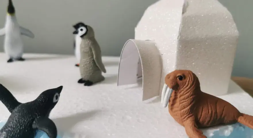 Maquette d'igloo blanc scintillant avec des figurines de phoques et de morses sur un décor de glace.