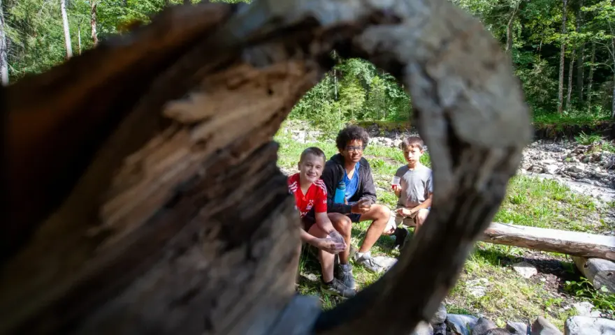 Trois enfants profitent d'une pause en forêt, rappelant l'importance du respect des locaux et de la nature.