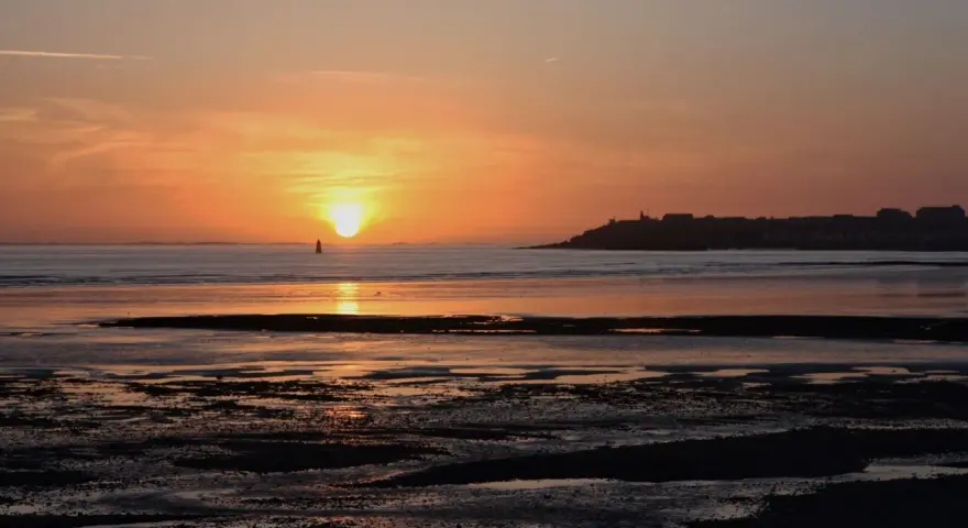 Coucher de soleil sur la mer à Saint-Pair-sur-Mer. La lumière dorée illumine le ciel et l'eau, invitant à la contemplation.