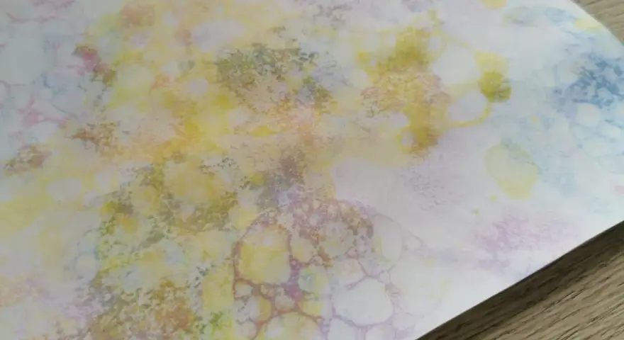 Peinture à bulles colorée sur papier blanc, avec des formes rondes et des éclaboussures.