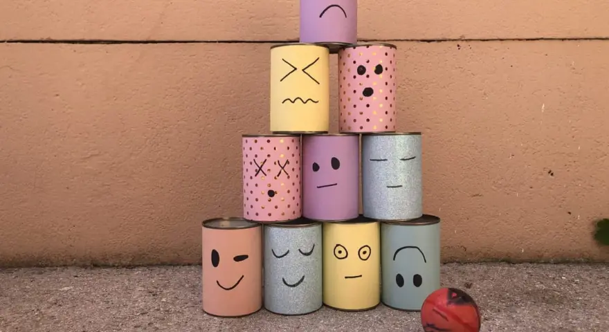 Pyramide de boîtes décorées de visages pour une kermesse chamboule tout. Un dessin amusant prêt à être renversé !