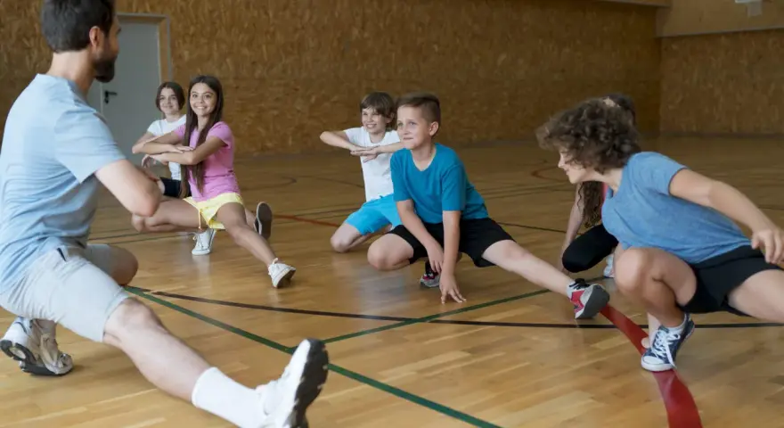 Un entraîneur guide des enfants lors d'une séance d'étirements. L'accueil des mineurs dans cette association sportive est une priorité.