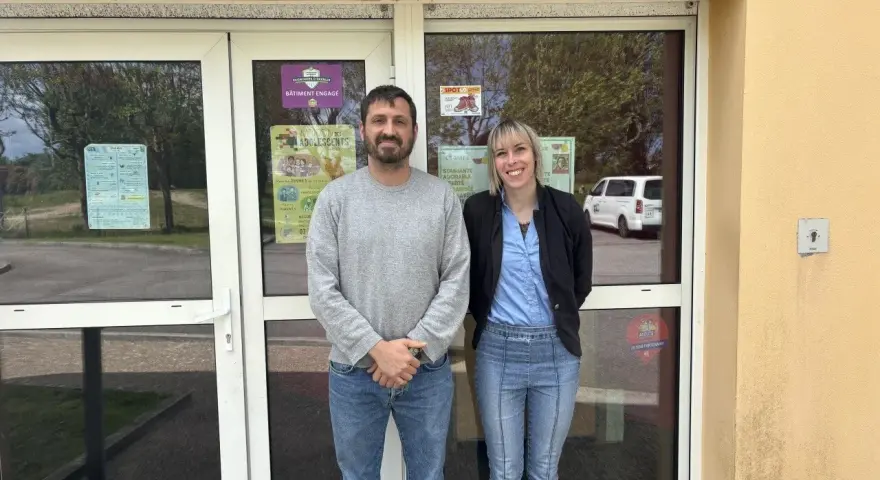 Le directeur du centre de loisirs et une collègue souriants devant l'entrée.