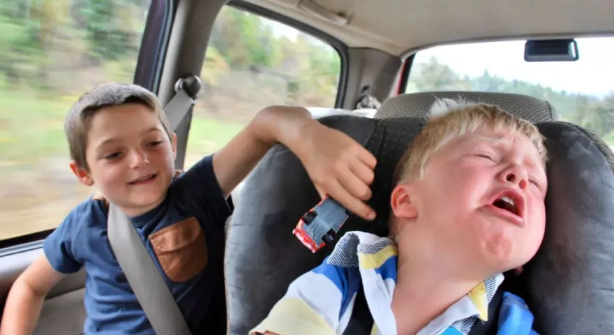 Un enfant pleure dans la voiture, son frère joue avec une petite voiture. Le temps de conduite chauffeur de bus est long pour certains.