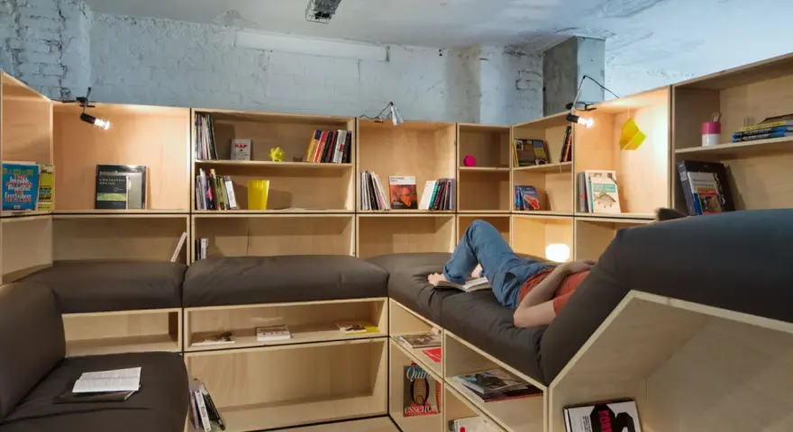 Aménagement d'une salle de loisirs avec étagères modulables et banquettes confortables.