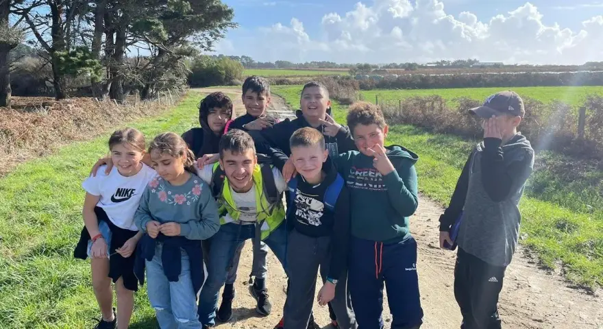 Groupe d'enfants souriants sur un chemin de terre, par une journée ensoleillée.