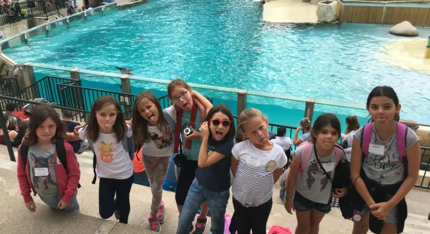 Des enfants en colonie de vacances en Île-de-France s'amusent devant un bassin de spectacle aquatique, faisant des grimaces.