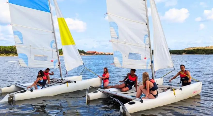 Des jeunes profitent d'une colonie de vacances voile, naviguant sur des catamarans par une journée ensoleillée.