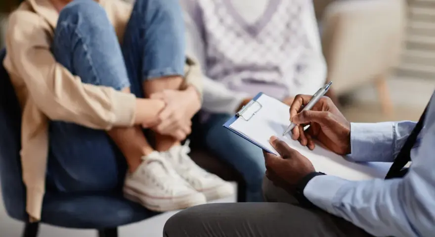 Un professionnel note des informations sur un jeune en difficulté, peut-être pour savoir comment faire une information préoccupante.