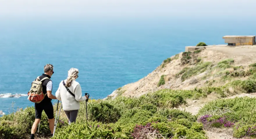 Couple randonnant sur les falaises de Jersey, profitant d'un séjour linguistique et d'une vue imprenable sur la mer.