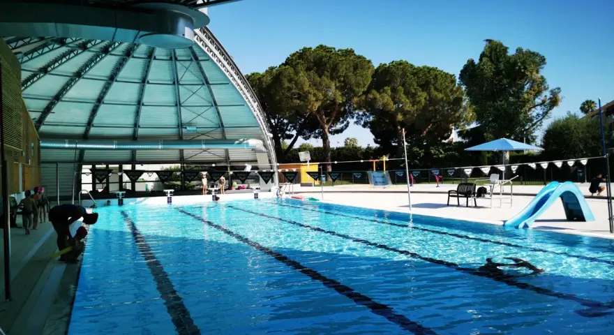 Piscine intérieure avec toboggan bleu, lignes de nage et quelques personnes.
