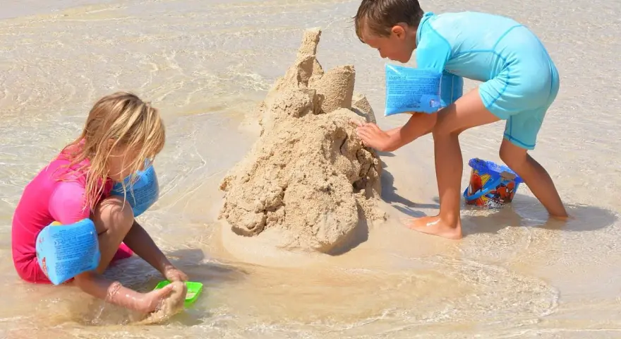 Enfants construisant un château de sable, une scène typique d'accueil centre de loisirs en bord de mer.