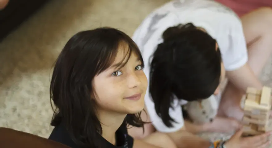 Deux enfants jouent à Jenga, une idée thème colonie. L'un regarde la caméra avec un sourire, l'autre est penché sur le jeu.