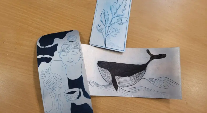 Trois gravures sur brique de lait : une femme, une baleine et une branche de chêne.