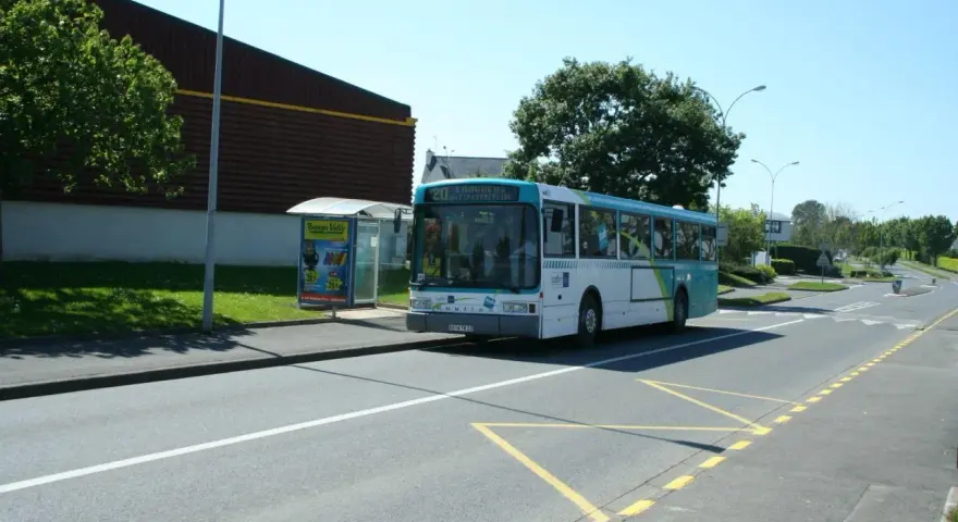 Un bus scolaire s'arrête à un arrêt de bus, respectant le code de la route. Le soleil brille sur la route.