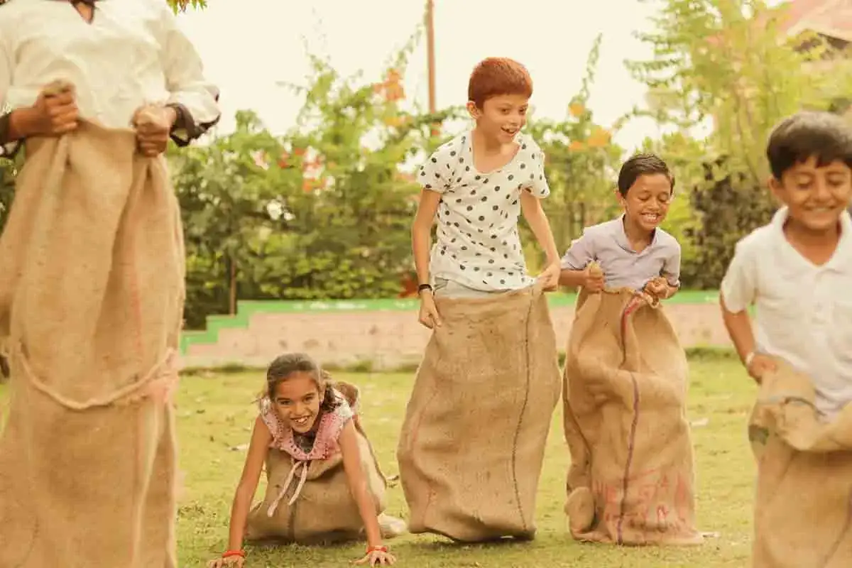 Des enfants s'amusent dans des sacs en toile de jute, une excellente idée animation fête de village pour des rires garantis !