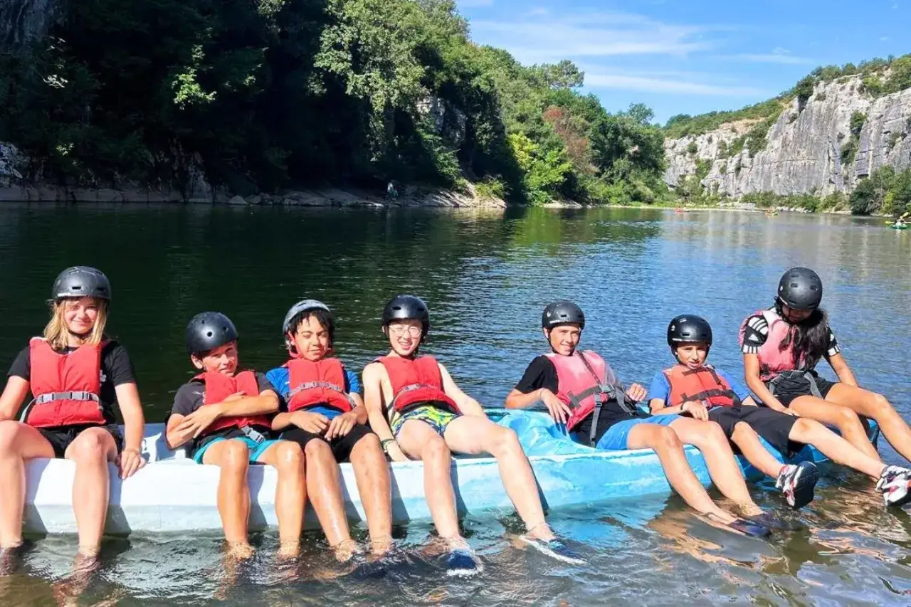 Enfants en gilets de sauvetage et casques, profitant d'une activité nautique lors d'une colonie de vacances 3-6 ans.