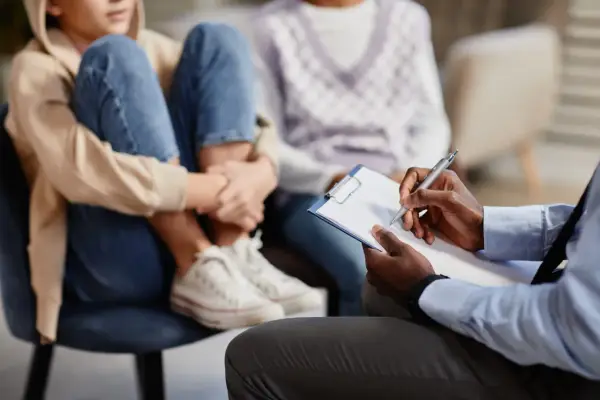 Un professionnel note des informations sur un jeune en difficulté, peut-être pour savoir comment faire une information préoccupante.